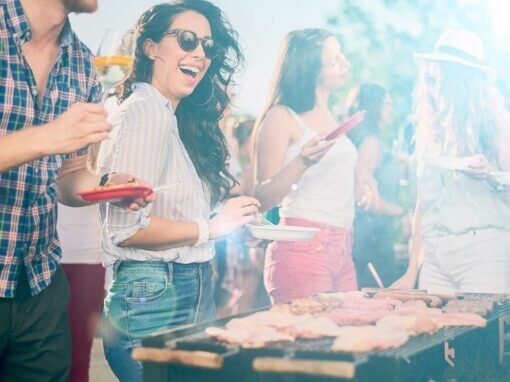 Quatre amis discutent autour d'un barbecue avec des assiettes à la main