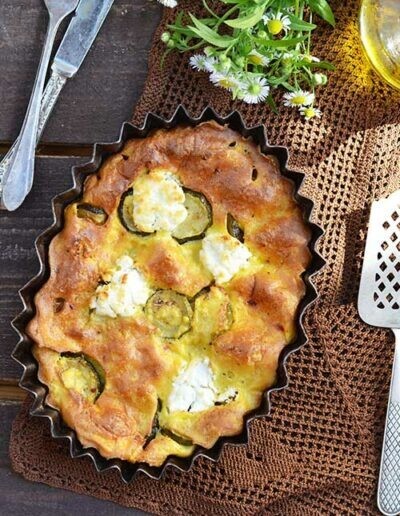 Une tarte à la courgette et au fromage dans un moule posée sur une table