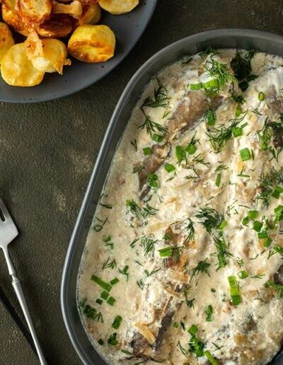 Plusieurs filets de poissons accompagné d'une sauce et d'herbes aromatiques présenté dans un plat gris